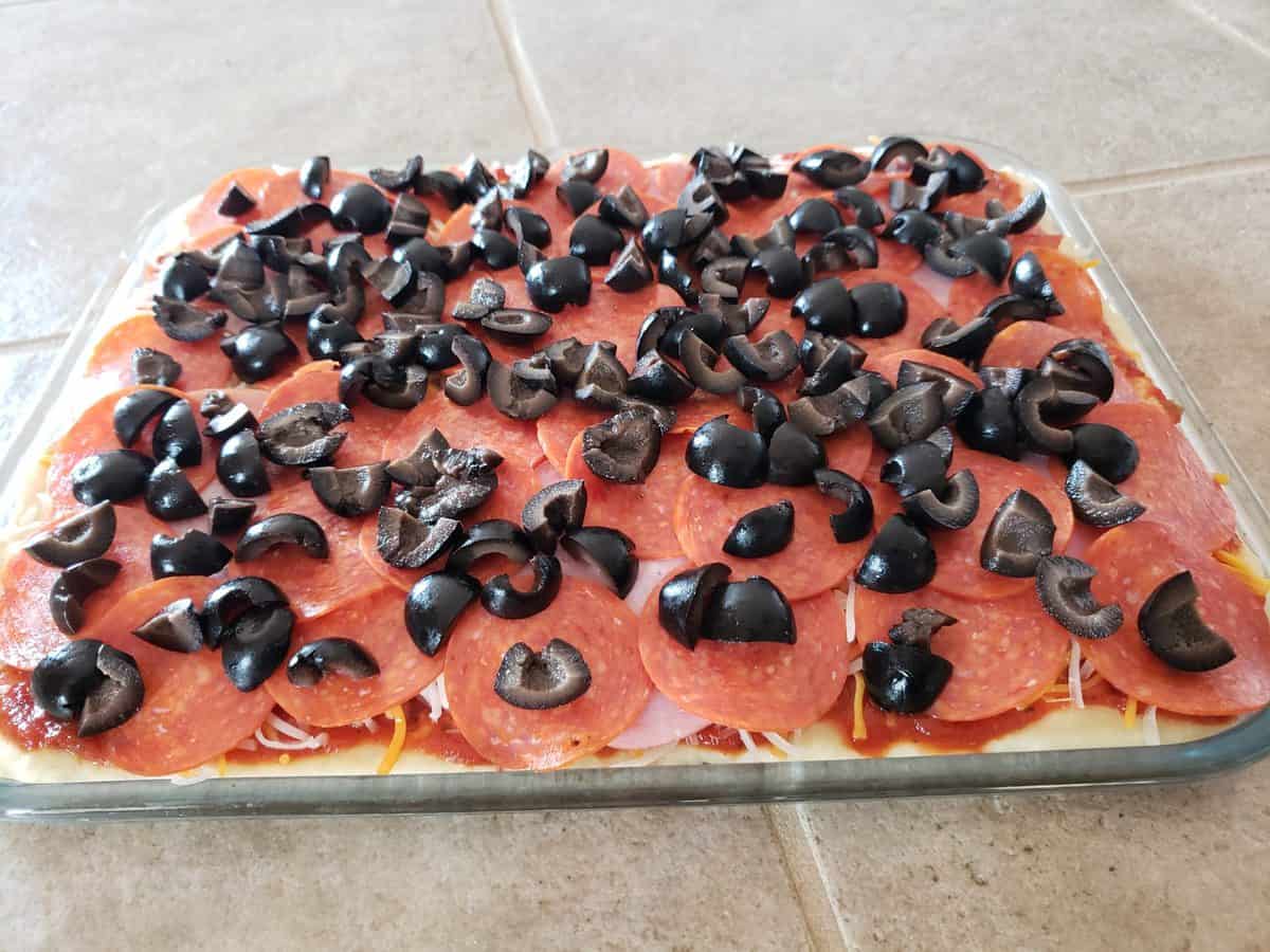 Add the black olives to the pizza.