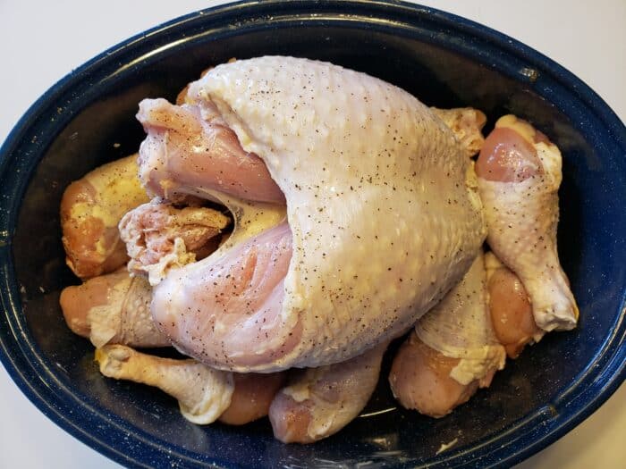 Raw turkey breast and turkey legs in a roasting pan.