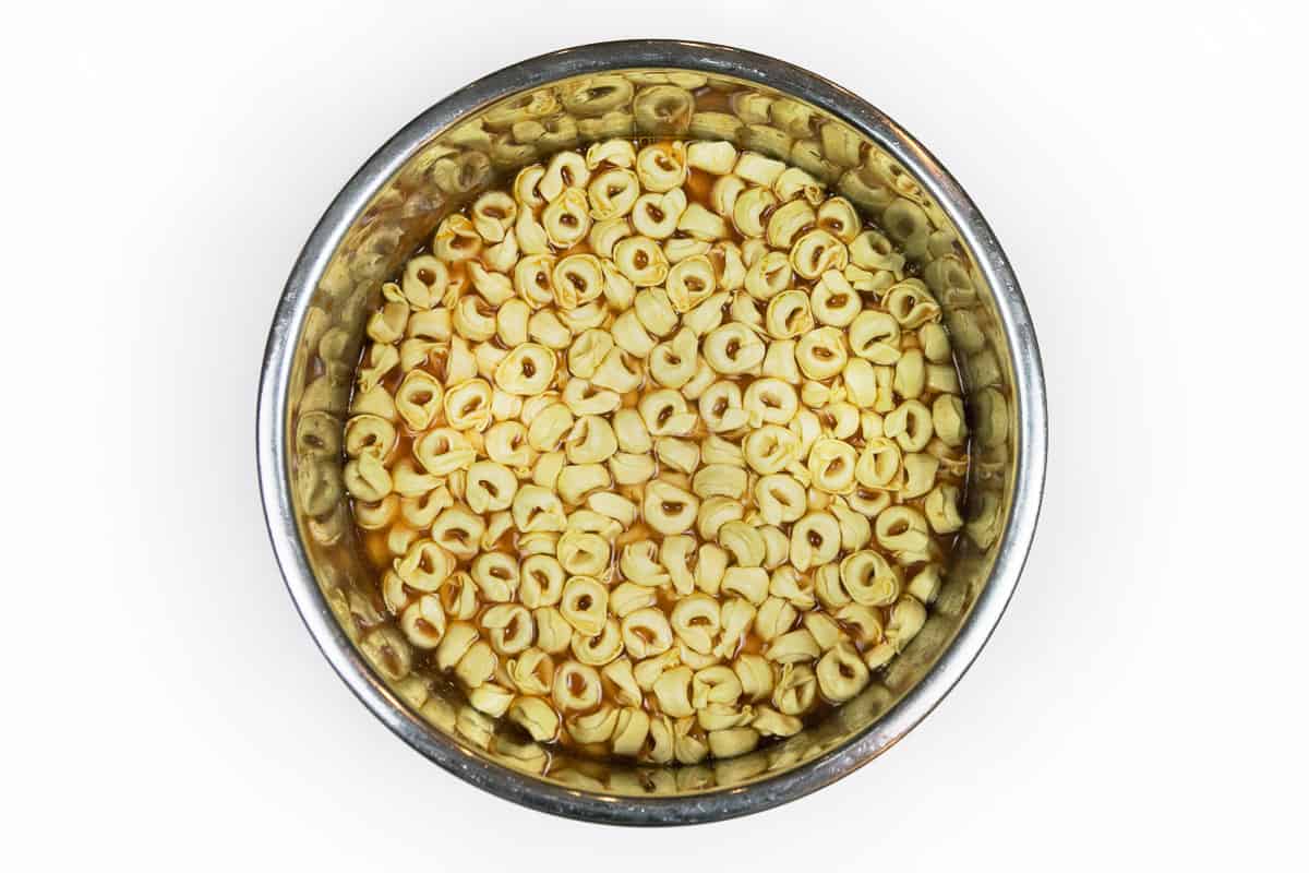 Water added the three cheese tortellini pasta, browned ground beef, pasta sauce, and diced tomatoes.