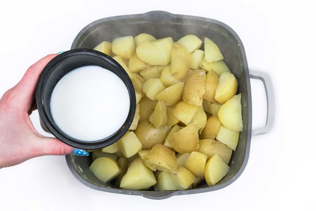 Add milk to cooked potatoes in saucepan.