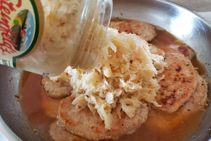 adding the sauerkraut to the pork chops