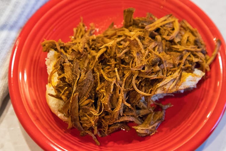 Barbeque Pulled pork instant pot over a bun on a plate.