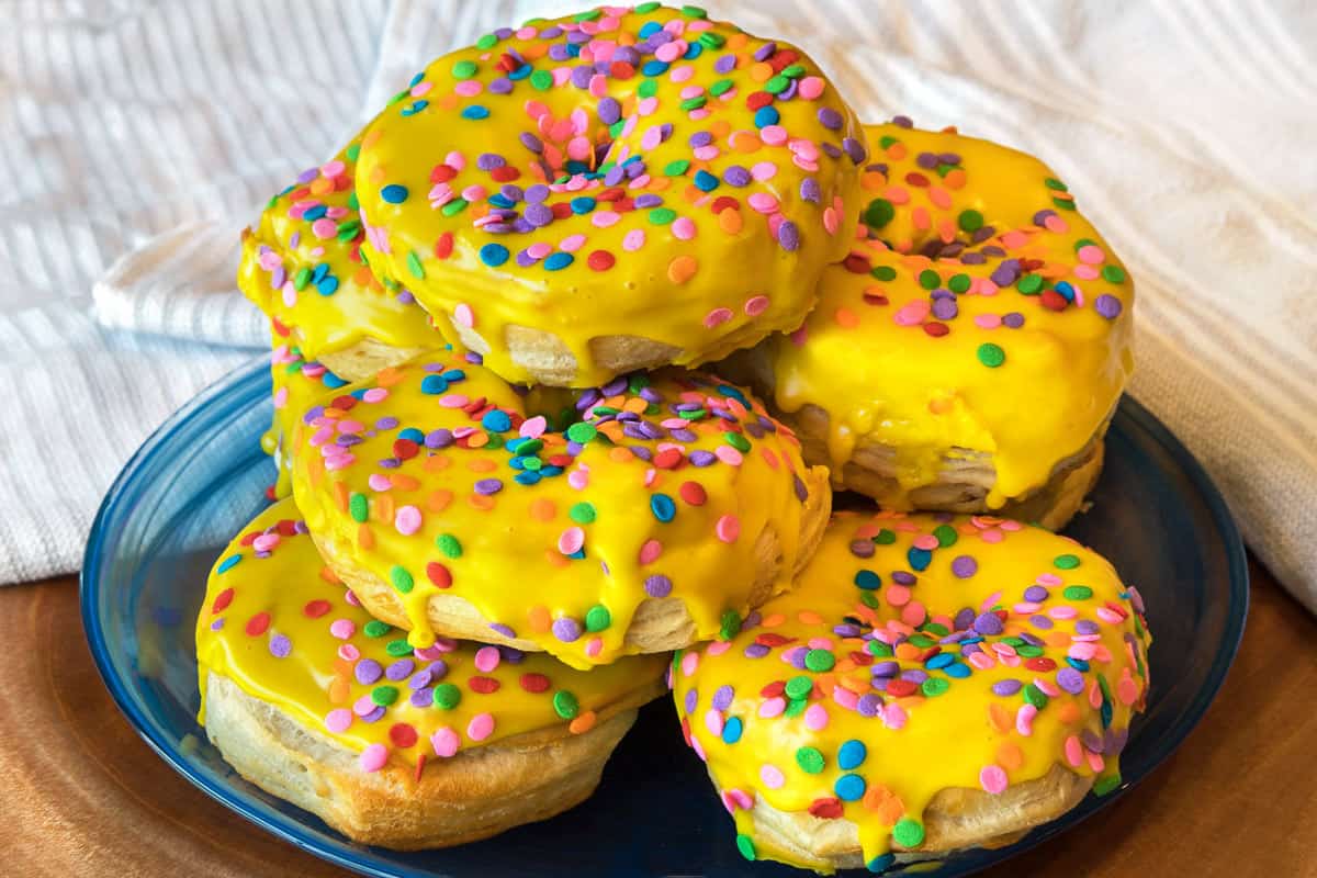 Easy air fryer biscuit donuts with yellow icing on a plate.