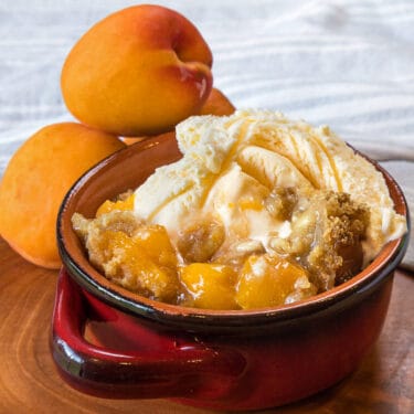 Apricot crisp recipe in a bowl with vanilla ice cream.