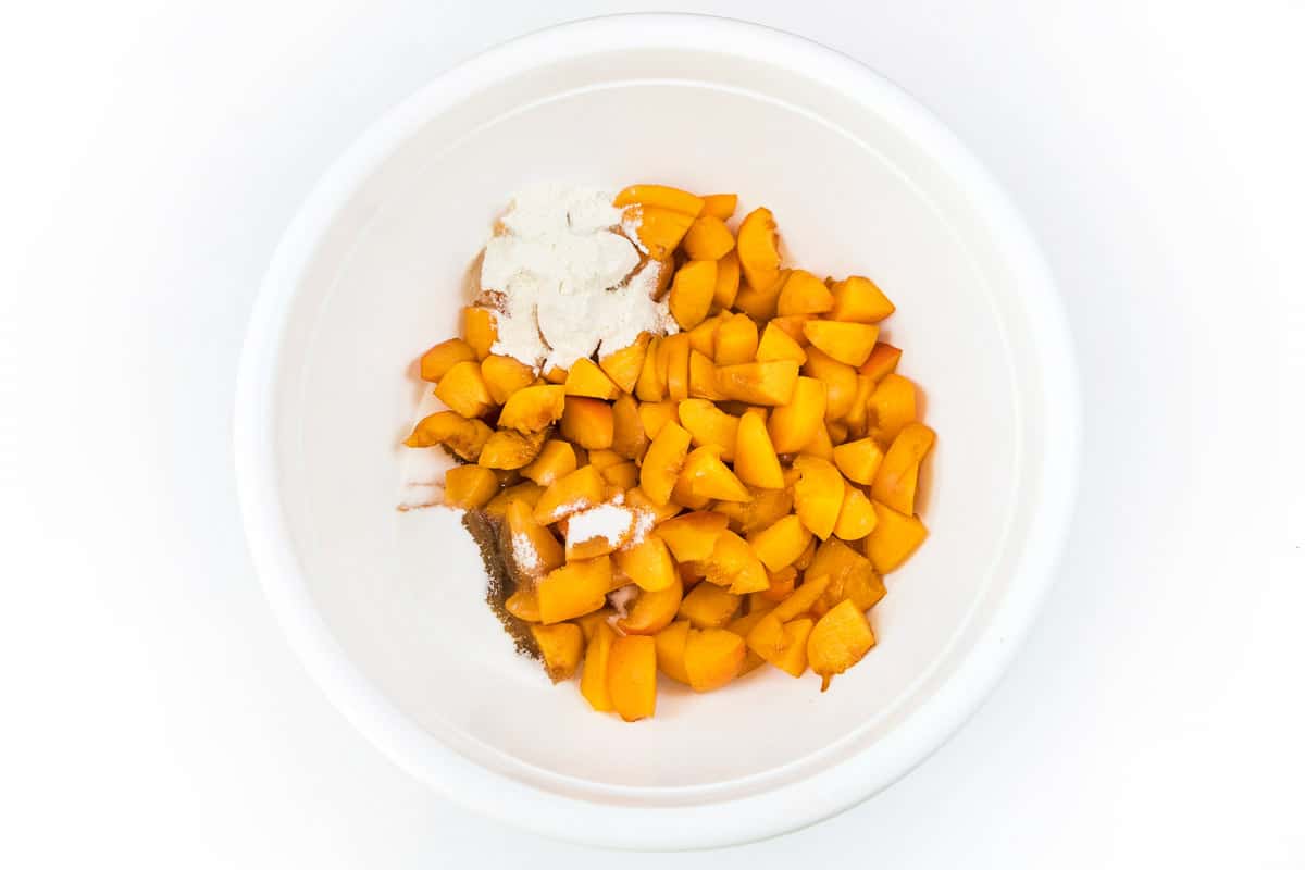 Add two teaspoons of lemon juice, one-half teaspoon of vanilla extract, two tablespoons of all-purpose flour, and one-third cup of granulated sugar to the cut-up apricots.