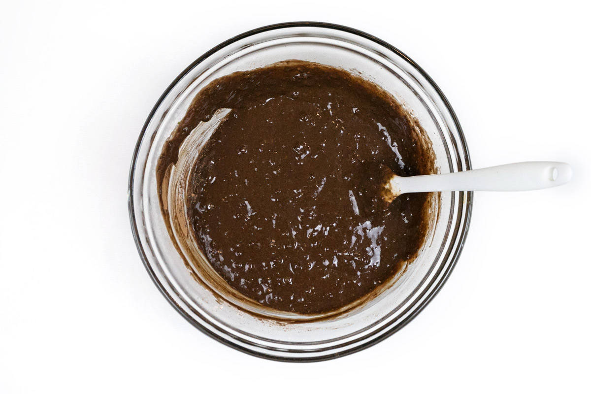 Unsweetened cocoa powder, honey, eggs, vanilla extract, and mashed avocado in a bowl.