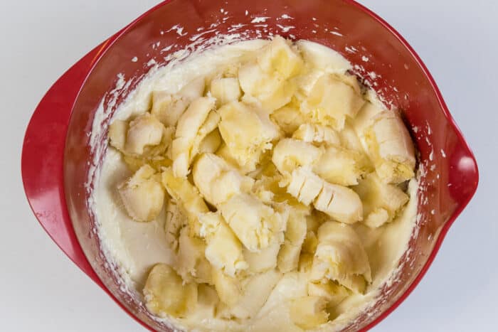 Four bananas are added to the eggs, melted butter, cream cheese, and sugar.