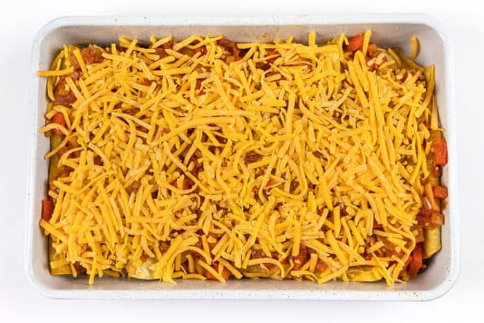 Sprinkle cheddar cheese over the top of the beef enchiladas then bake in the oven at three hundred and fifty degrees for thirty minutes.