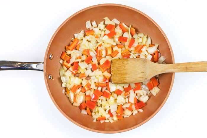 Add the chopped red bell pepper to the onions in the frying pan.