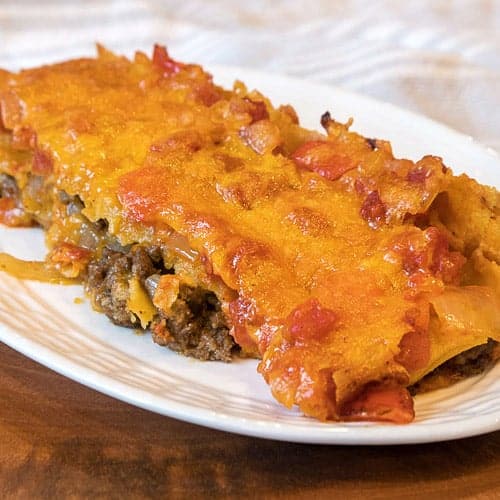 Beef enchiladas and peppers on a plate.