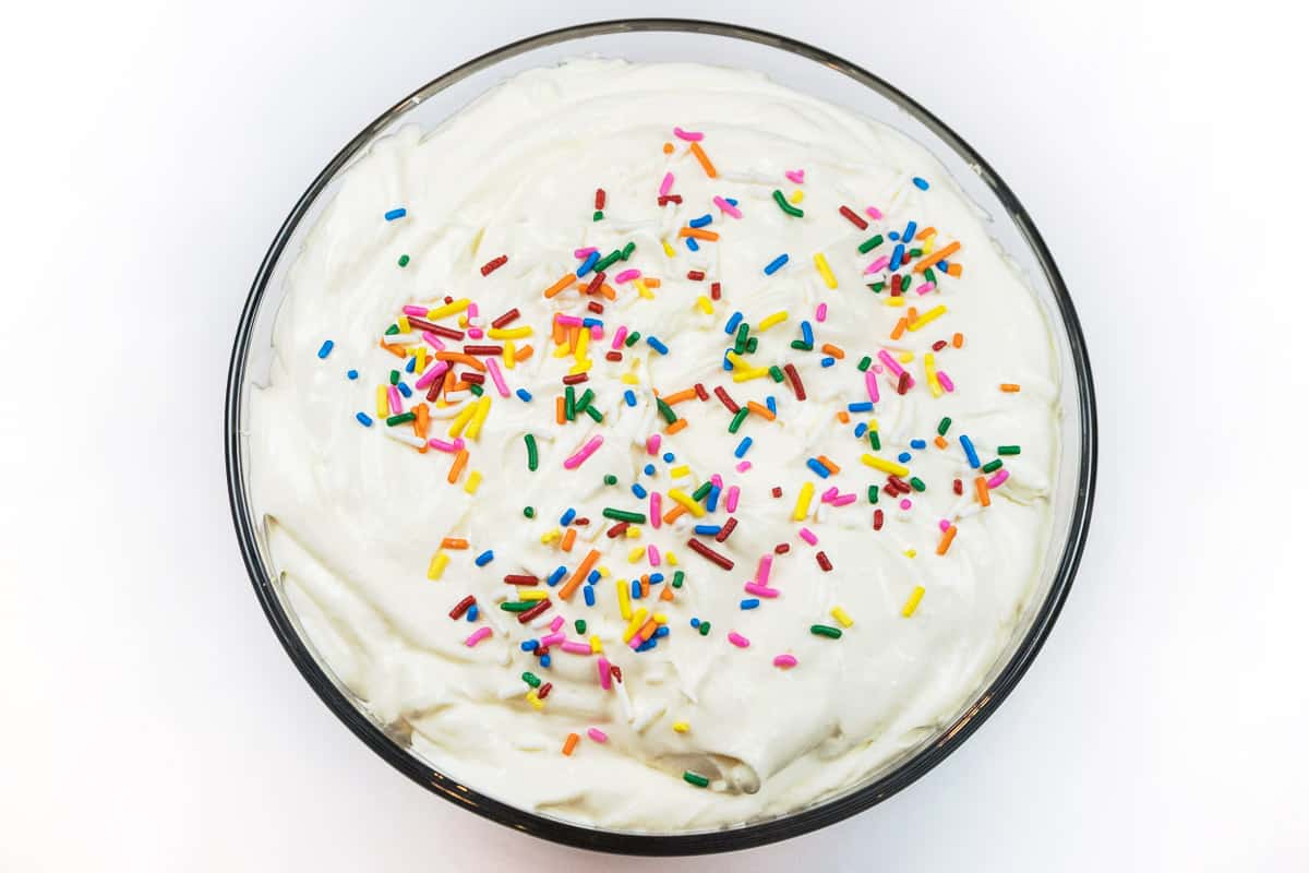 For the fourth layer, spread the last half of the cheesecake cream cheese pudding mixture over the cake and shake sprinkles on the top.