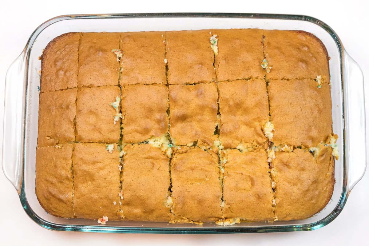 The cake is baked and cut into eighteen squares.