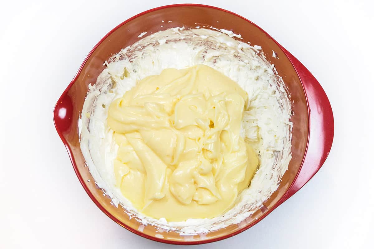 The cheesecake pudding is added to the cream cheese and whipped topping in the other bowl.