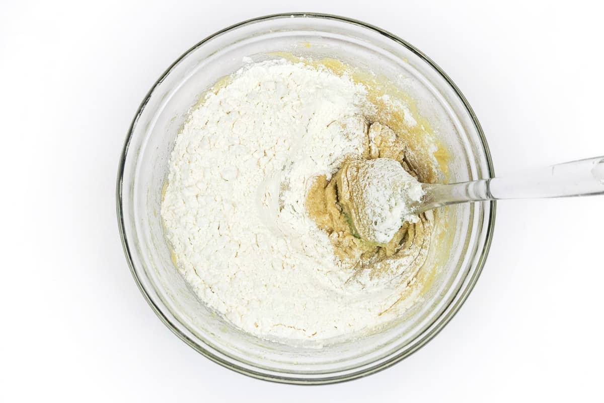 The flour mixture is slowly added to the eggs, vanilla extract, softened butter, granulated sugar, and light brown sugar.