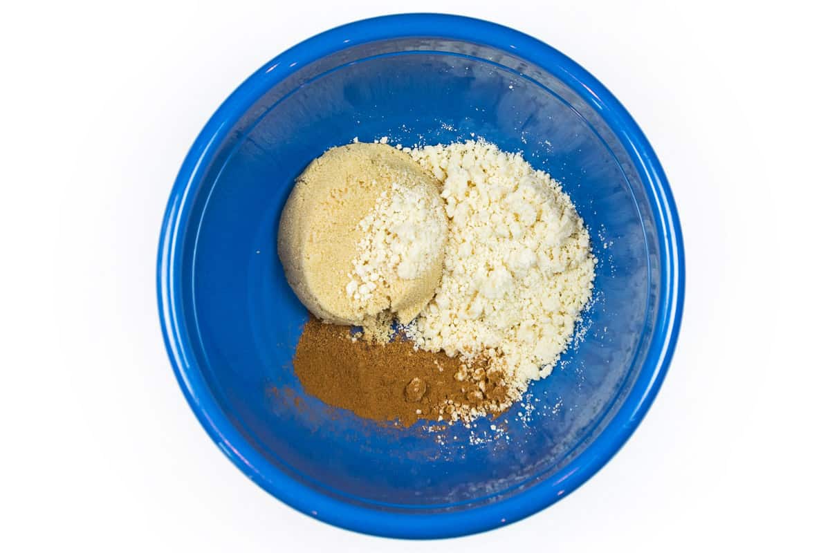 Crumbly mixture, brown sugar, cinnamon, and nutmeg in a bowl.