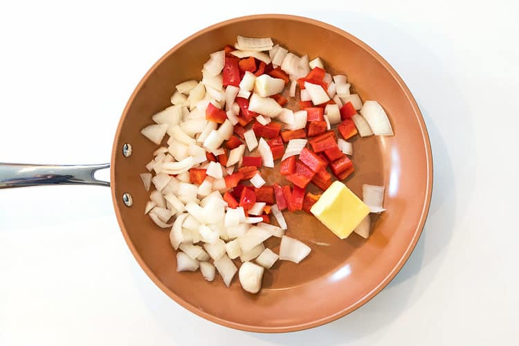 Diced onions, red bell peppers, and butter in a skillet.