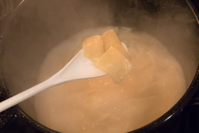 Dumplings cooking in pot of water.