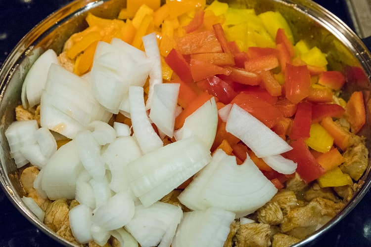 Add the bell peppers and onions to the frying pan with the chicken.