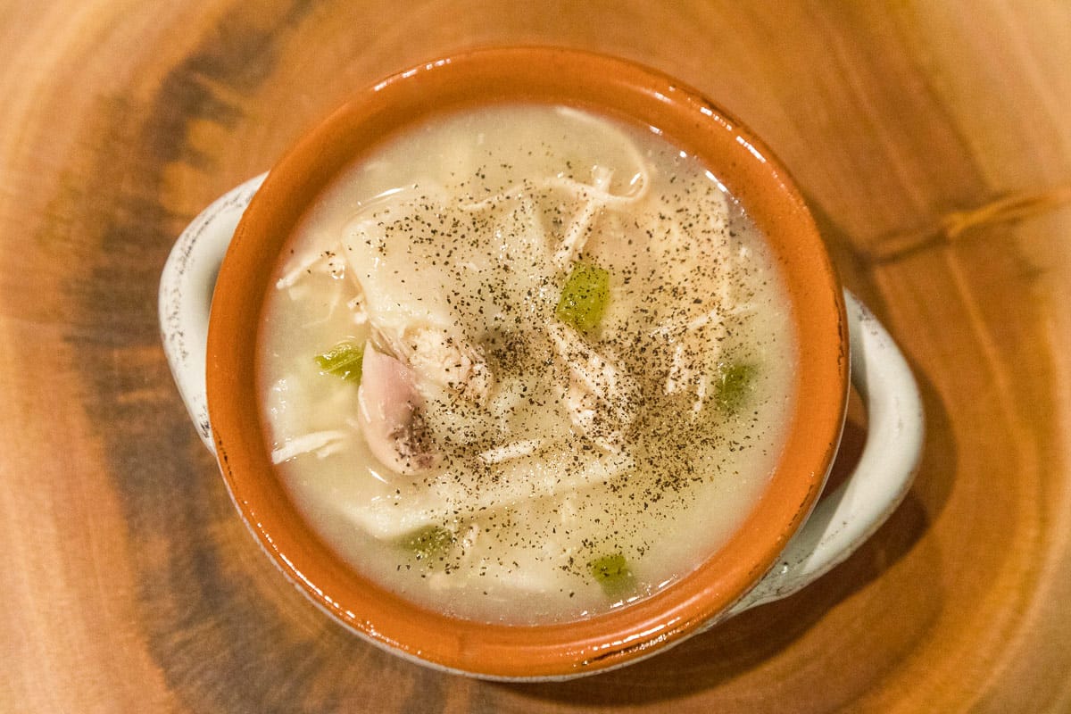 Chicken and dumpling soup in a bowl with pepper on top.