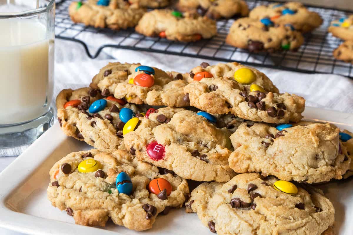 Chocolate chip M&M cookies on a plate with a glass of milk.