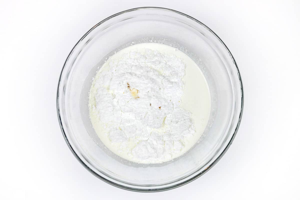 Heavy whipping cream, powdered sugar, and vanilla extract in a bowl.