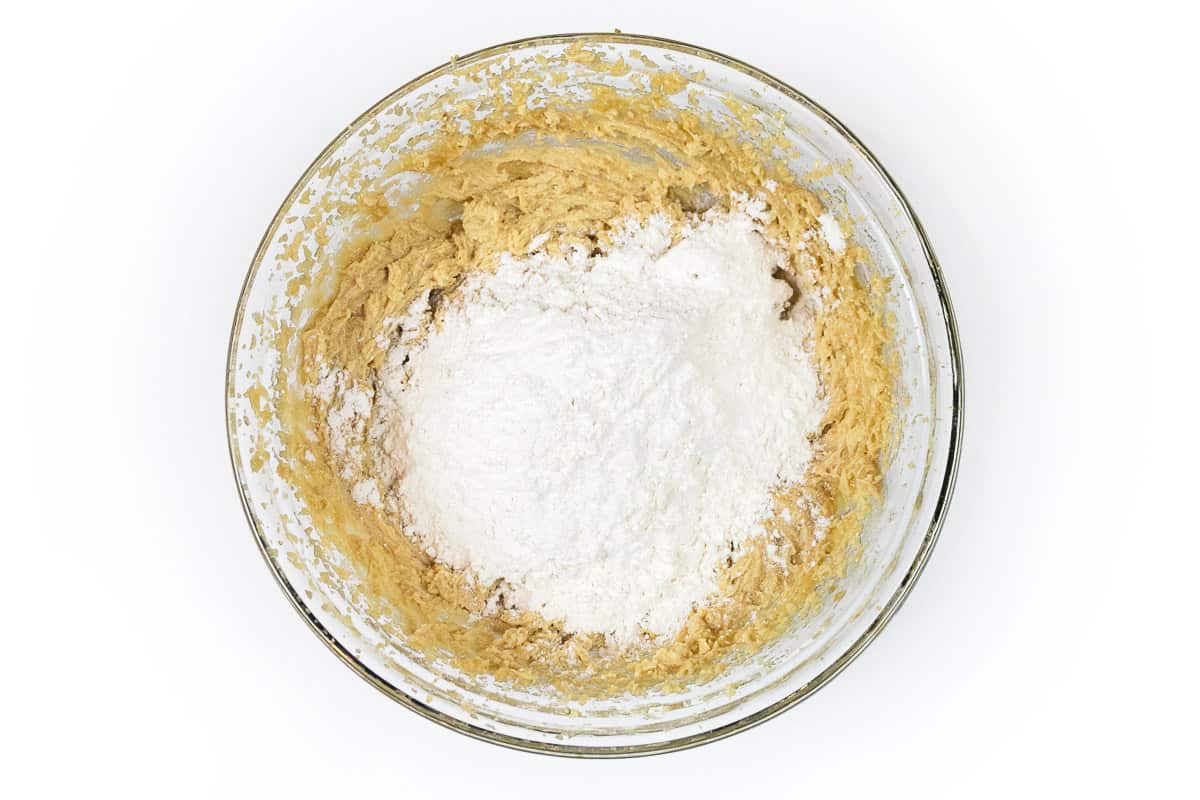 The flour mixture is added to the butter and sugar mixture in the bowl.