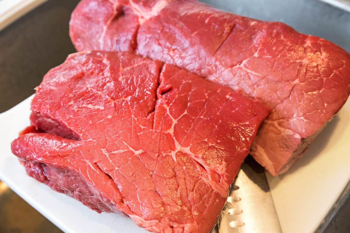 Between three to five pounds of chuck roast on a cutting board.