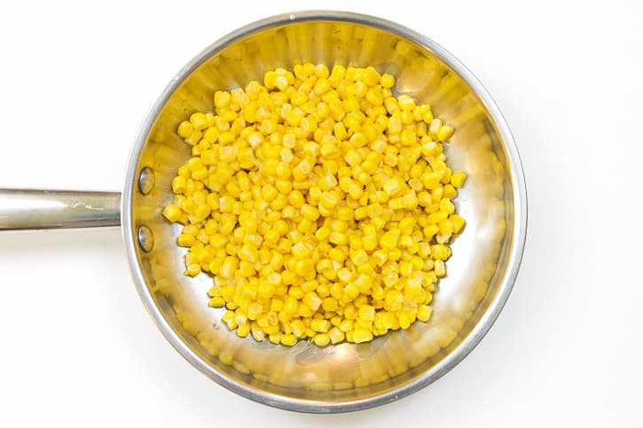 One can of corn and two tablespoons of olive oil in a frying pan.