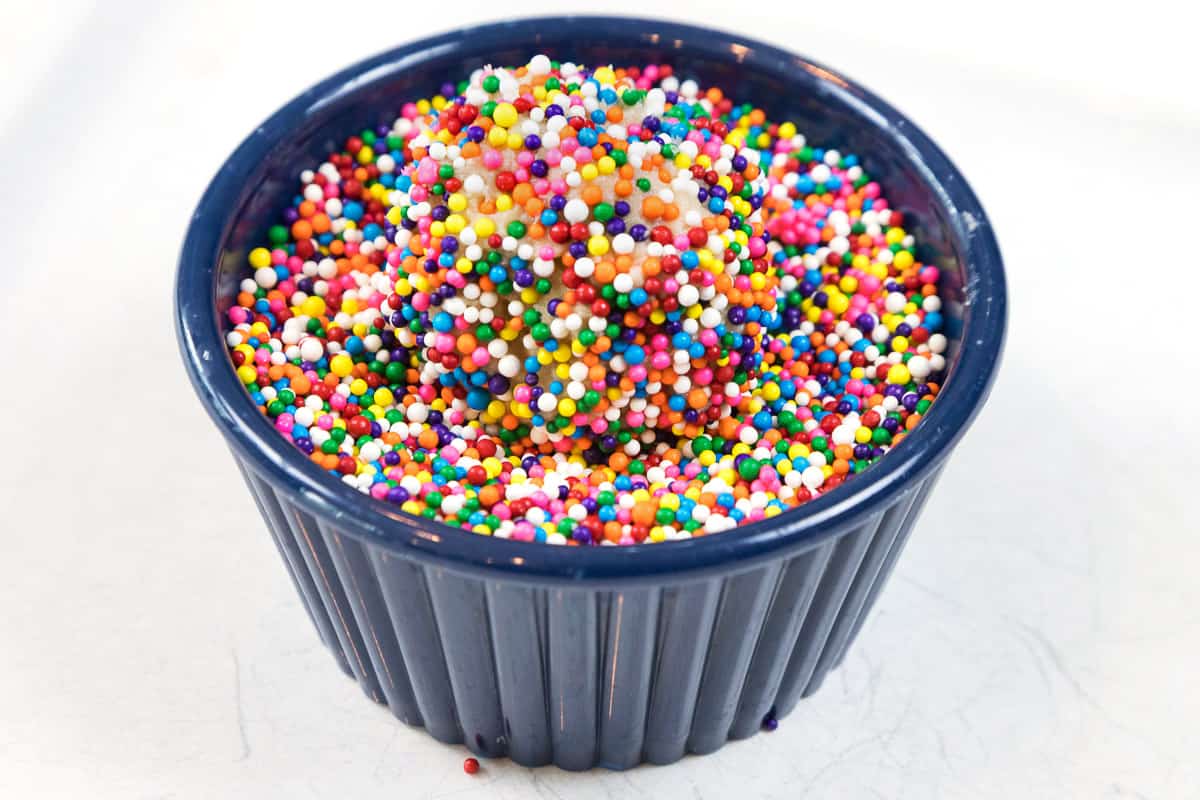 Roll the ball of cookie dough in the bowl of sprinkles.