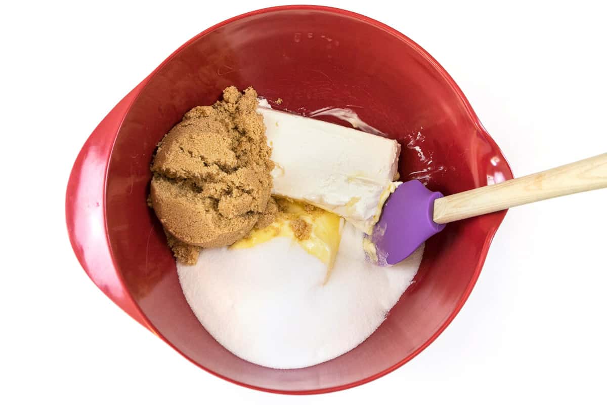 Three-fourths of a cup of softened butter, one cup of light brown sugar, one cup of granulated sugar, and an eight-ounce brick of softened cream cheese in a bowl.