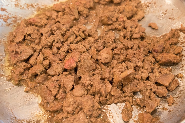 The liver is browning in the frying pan with some pink showing.