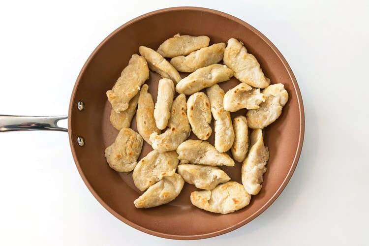 Dumplings are browning in a frying pan.