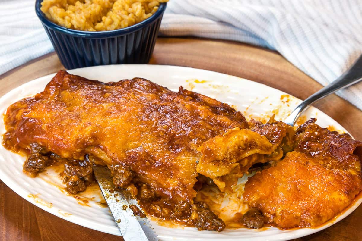 A ground beef enchilada on a plate.