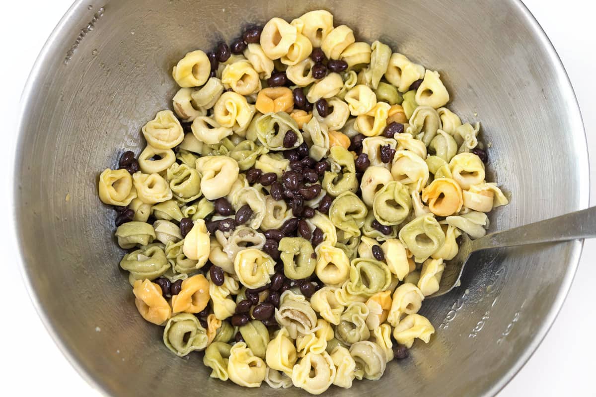 Tortellini pasta, black beans, and olive oil in a bowl.