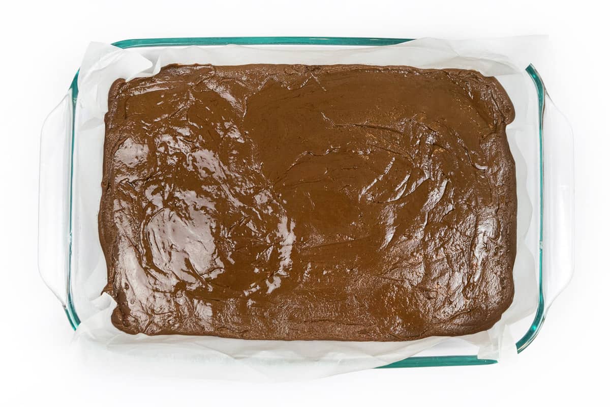 The fudge is poured over the parchment paper in the baking dish.