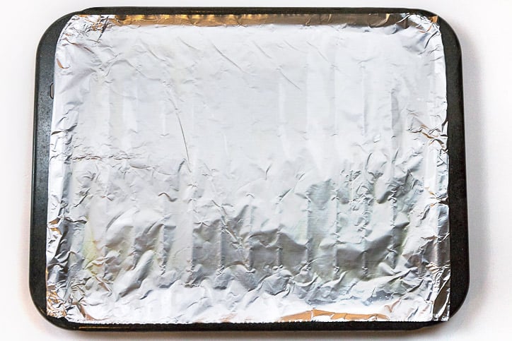 A broiler pan with aluminum foil on it.