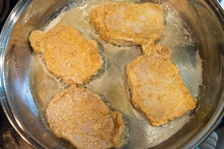 Fried Pork Chops Recipe in the frying pan. Pork chops frying in the frying pan for four to five minutes on each side. Check the internal temperature to make sure the temperature is at 145 degrees. If not cook a few more minutes.