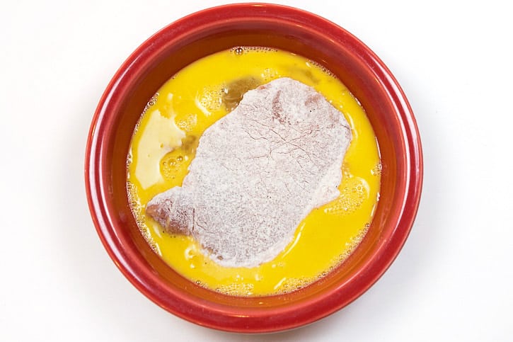 Dip the floured pork chop in the bowl of beaten eggs.