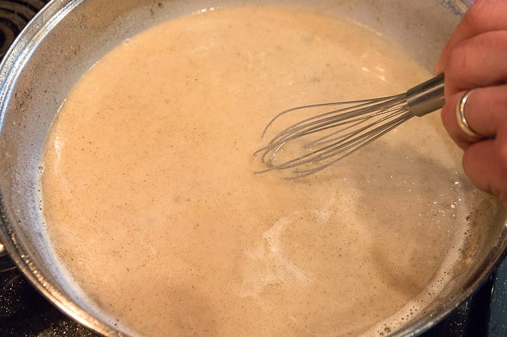 Add two and a half cups of water and one-half cup of milk with the browned flour mixture. Whisk it constantly.