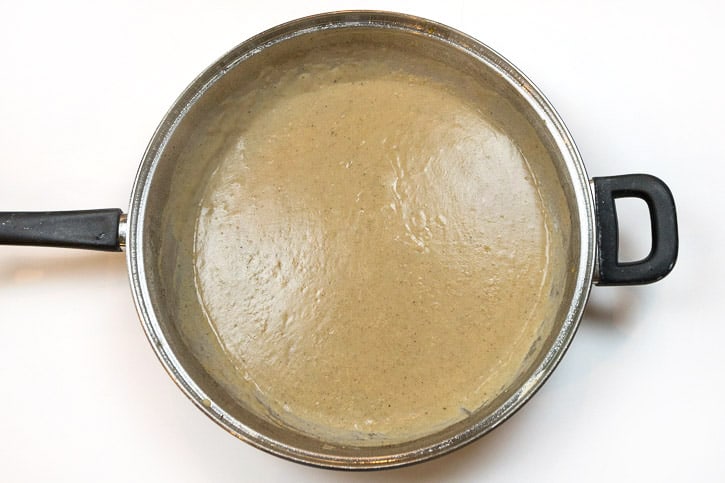 About two and a half cups of pork chop gravy in a frying pan.