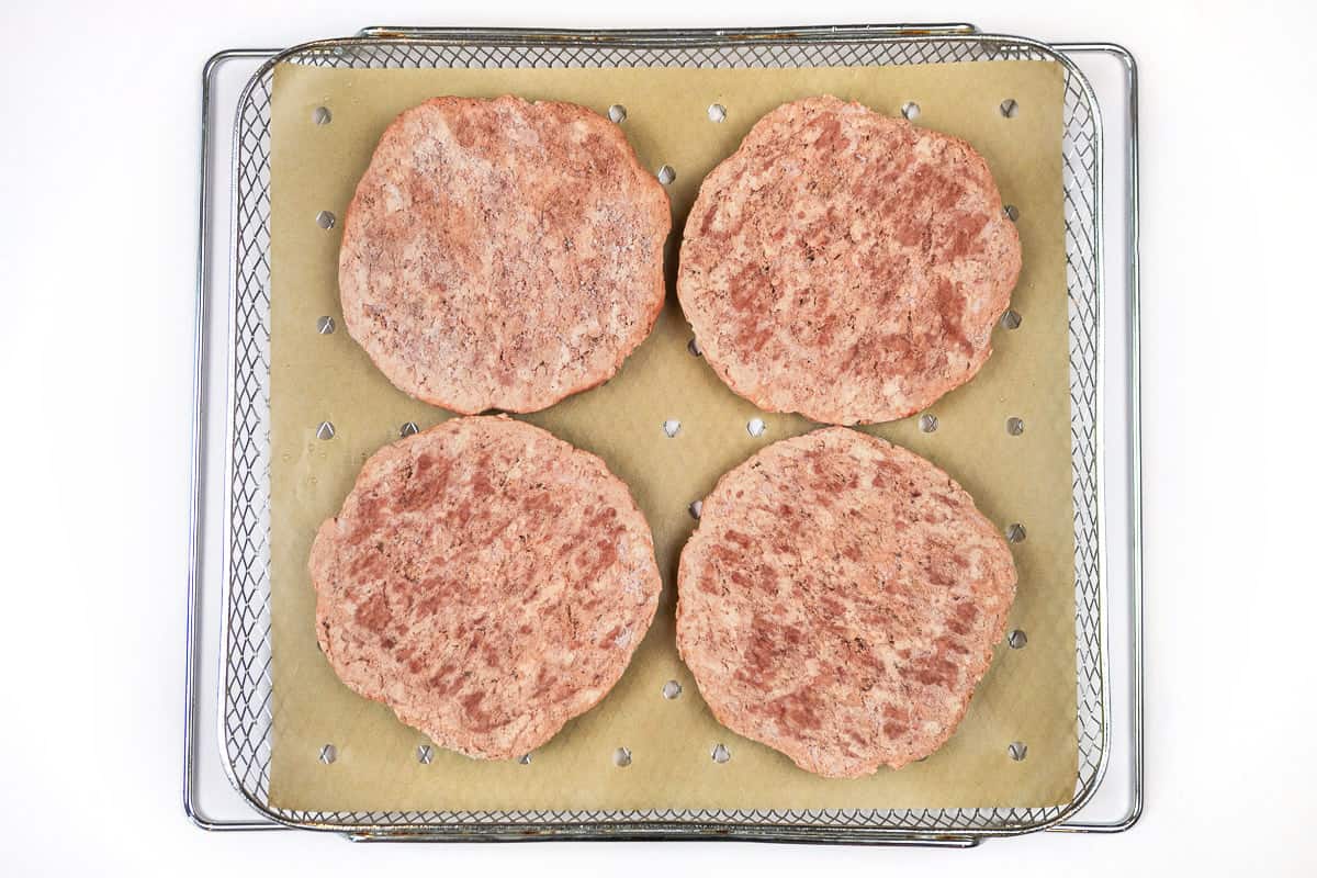 Place four hamburger patties on top of the parchment paper.
