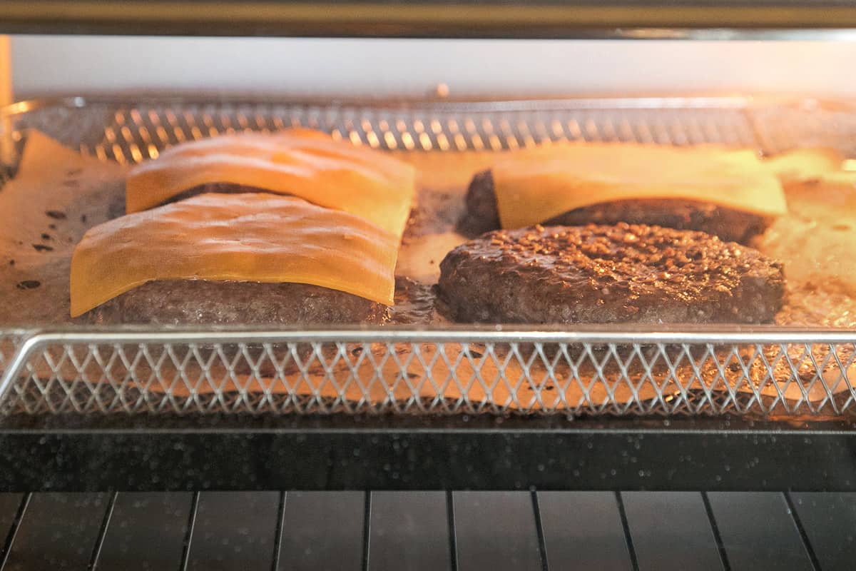 Cheese melting on the hamburger patties in the air fryer.