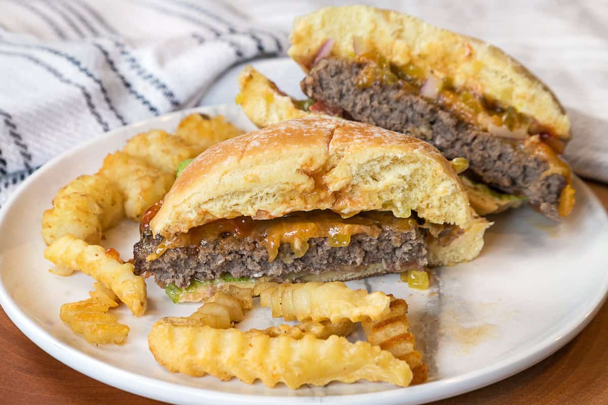 A hamburger cut in half with all of the trimmings on a plate.