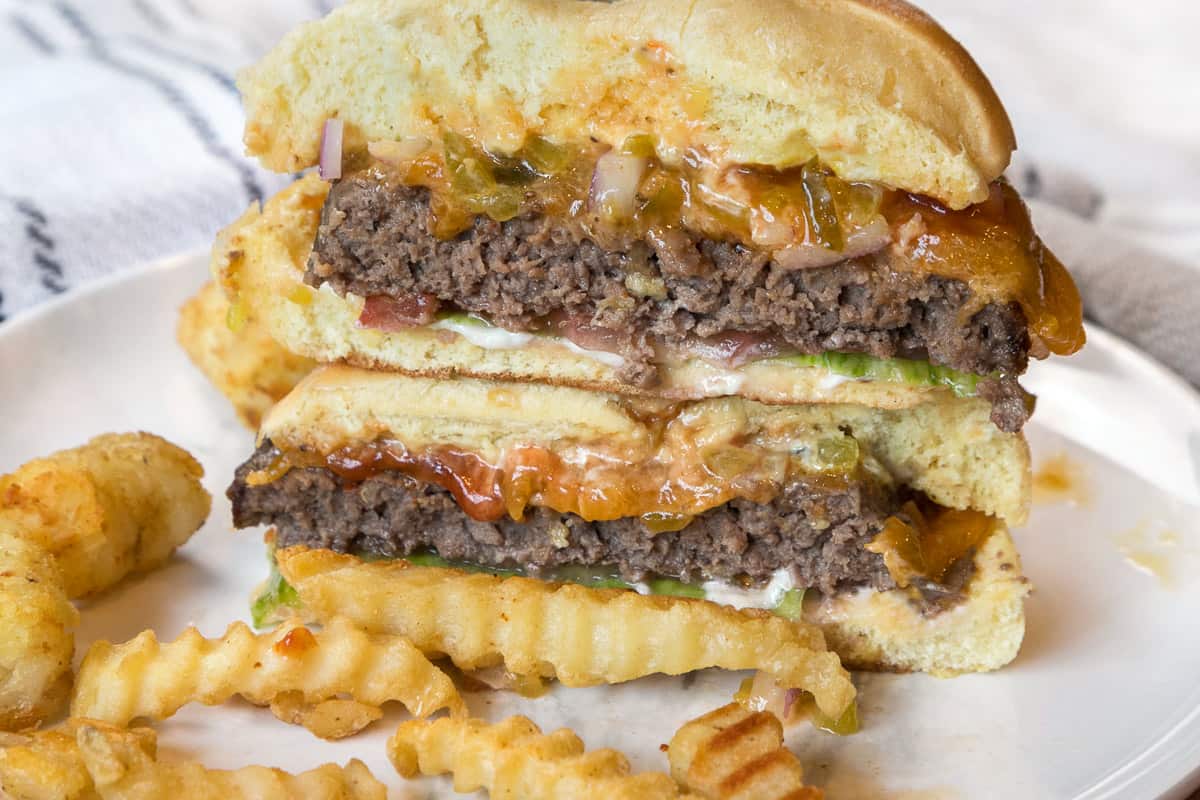 A hamburger cut in half with all of the trimmings on a plate