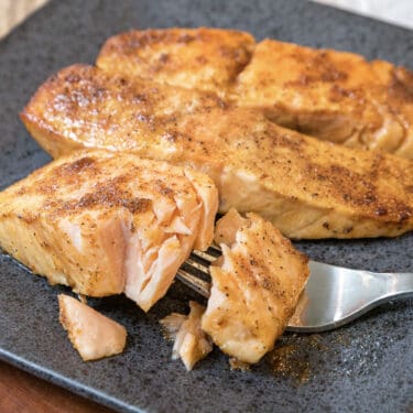 Frozen salmon cooked in the air fryer recipe close up on a black plate.