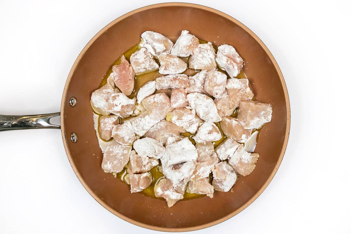 Add the chicken pieces to the frying pan with the olive oil.