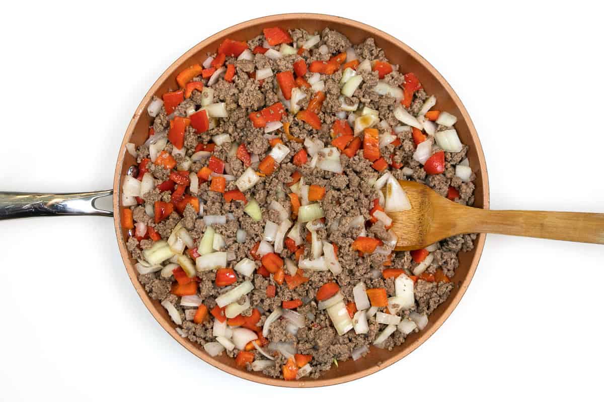 The diced red bell peppers and diced onions are simmered until tender with the browned ground beef.