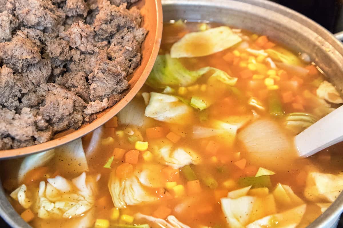 Add the browned ground beef to the pot of soup.