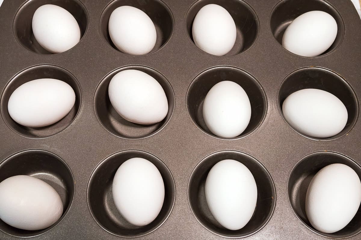 A twelve-cup muffin pan with one egg in each cup.