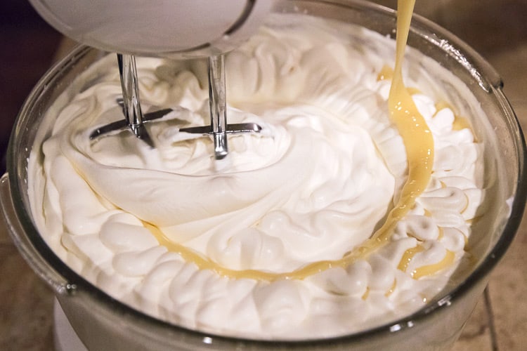 Two cans of condensed milk, each 14 ounces, is added to the whipping cream with the mixer on low speed.